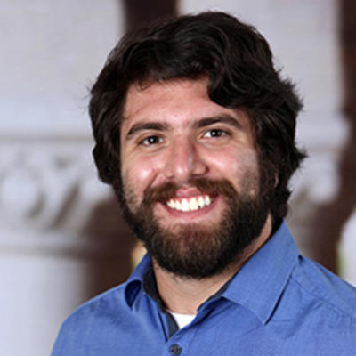 Photo of Dr. Munoz-Najar Galvez, a smiling man in a blue shirt with dark hair and a beard.