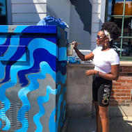 Artist Erica Imosi looking on at her Blue, wave designed PaintBox